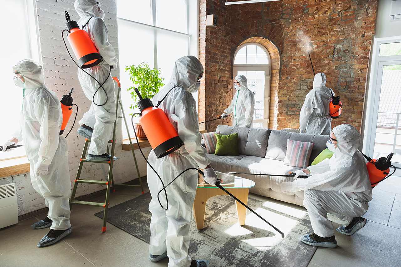 Coronavirus Pandemic. A disinfectors in a protective suit and mask sprays disinfectants in the house or office